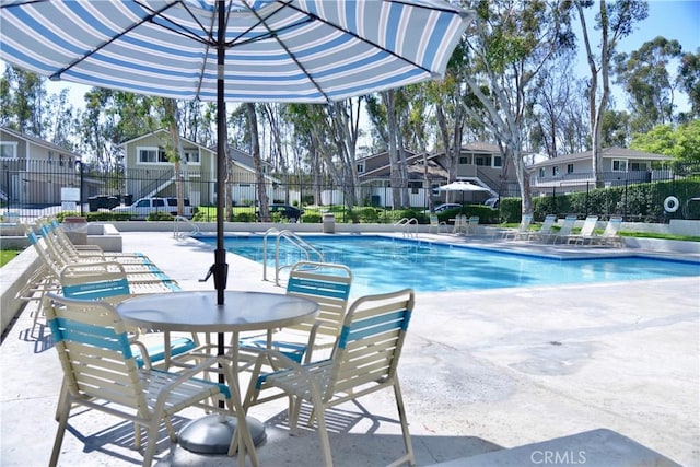 pool featuring fence, a patio area, and a residential view