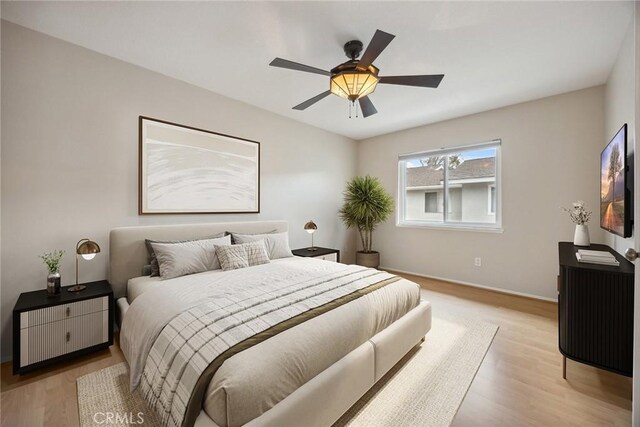 bedroom featuring baseboards, ceiling fan, and light wood finished floors