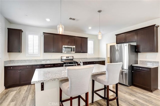 9126 Foster Ln, Chatsworth, CA 91311 - kitchen with stainless steel appliances, dark brown cabinetry, light wood-style flooring, a breakfast bar, and recessed lighting