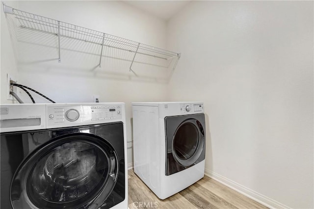 9126 Foster Ln, Chatsworth, CA 91311 - laundry area with washer and clothes dryer, light wood-style floors, and baseboards