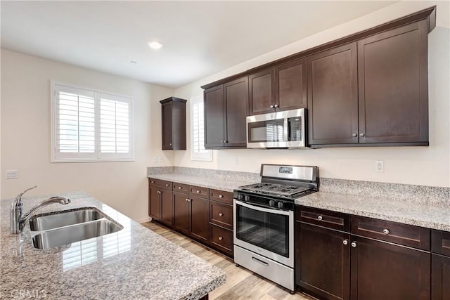 9126 Foster Ln, Chatsworth, CA 91311 - kitchen with stainless steel appliances, a sink, light wood-style floors, dark brown cabinetry, and light stone counters