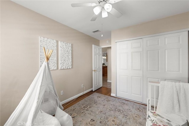 bedroom featuring a closet, ceiling fan, visible vents, baseboards, and wood finished floors