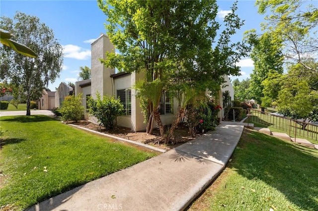 view of home's exterior with a lawn, stucco siding, and fence