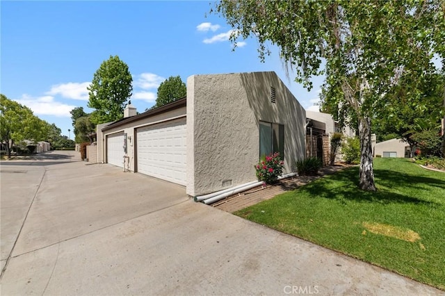 view of property exterior with a garage, stucco siding, and a yard