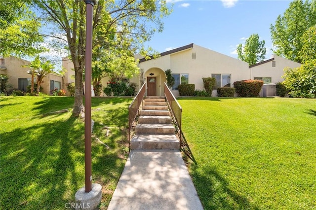 mediterranean / spanish-style house with a front yard, central air condition unit, and stucco siding