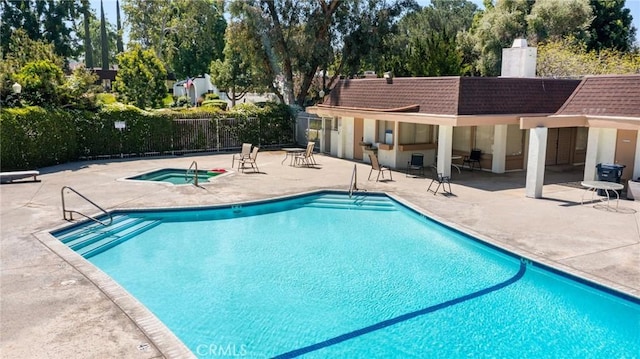 community pool featuring a patio, a community hot tub, and fence