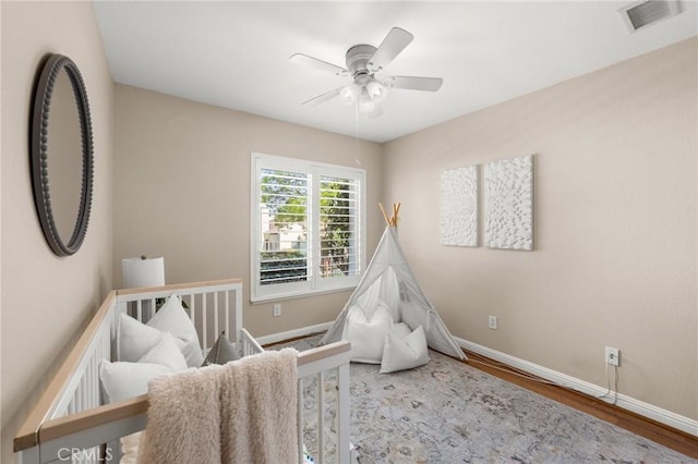 bedroom with a ceiling fan, visible vents, wood finished floors, and baseboards