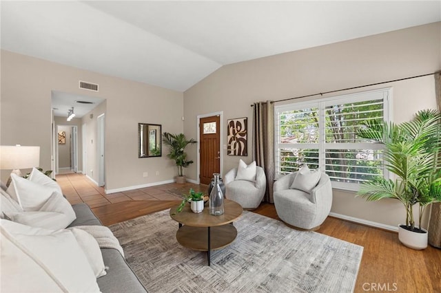 living room featuring visible vents, vaulted ceiling, wood finished floors, and baseboards