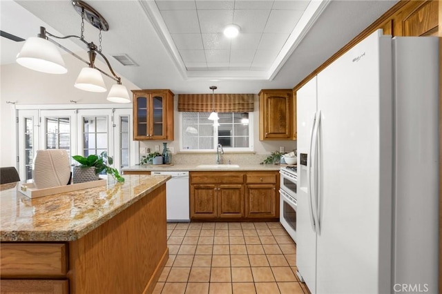 kitchen featuring white appliances, brown cabinets, a sink, visible vents, and a tray ceiling