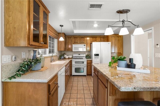 kitchen featuring a sink, glass insert cabinets, brown cabinetry, visible vents, and white appliances