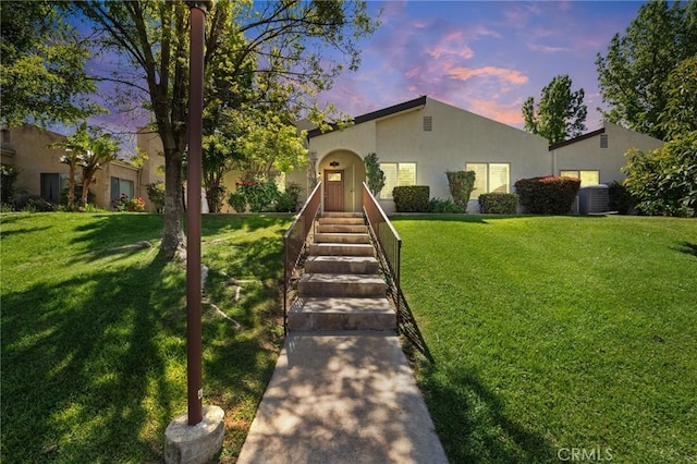 mediterranean / spanish house with stucco siding, central air condition unit, and a front lawn