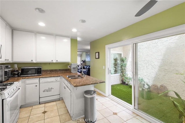 kitchen with white cabinetry, a sink, a peninsula, white appliances, and light tile patterned flooring