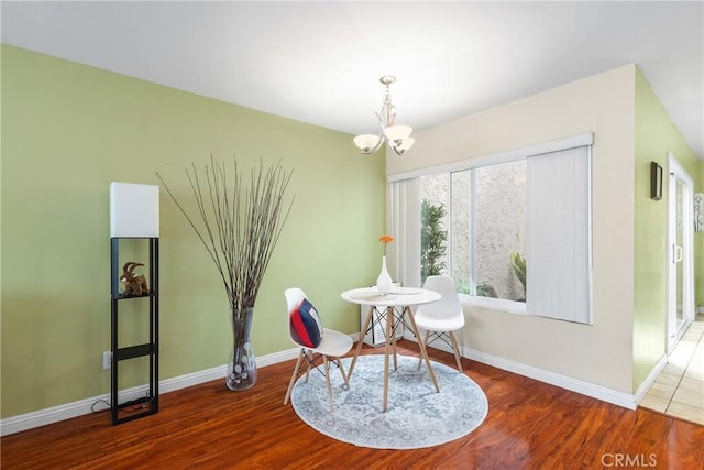 dining area featuring baseboards, a chandelier, and wood finished floors