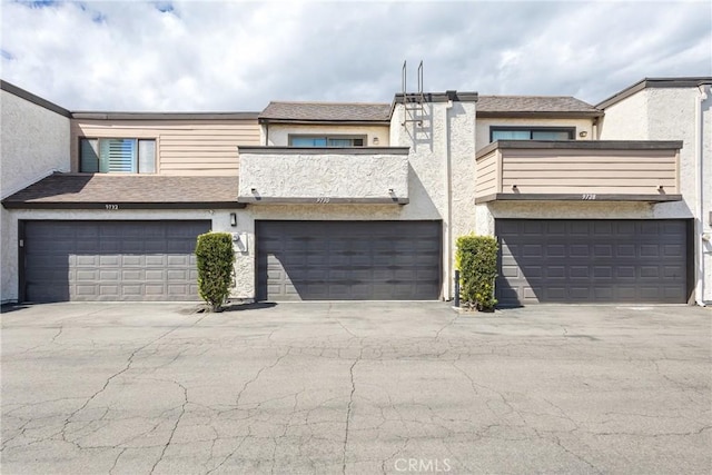 view of property with an attached garage, driveway, and stucco siding
