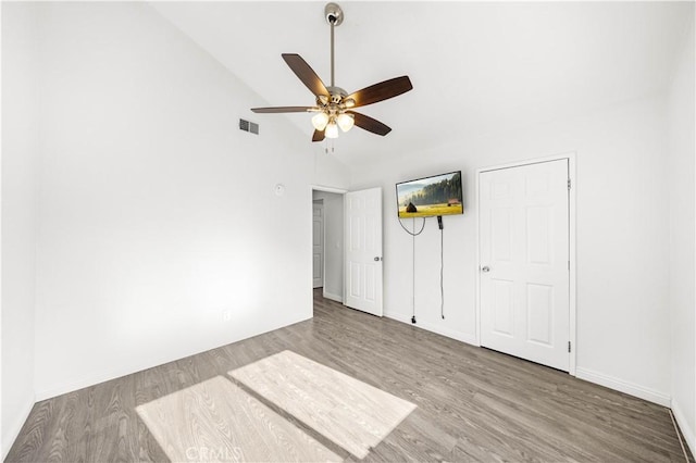 unfurnished bedroom with baseboards, visible vents, wood finished floors, and high vaulted ceiling