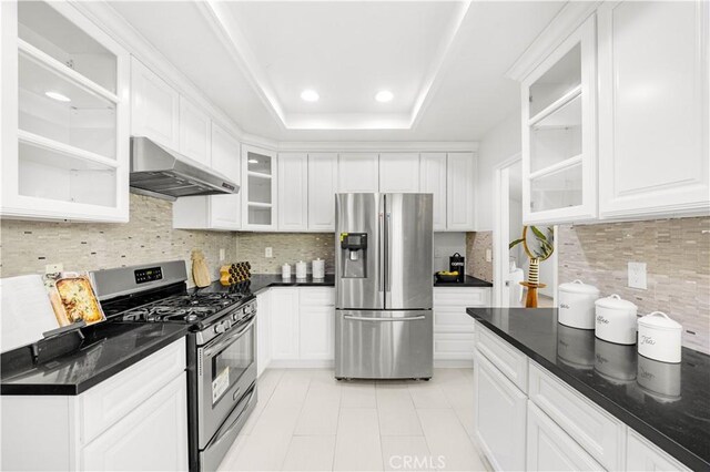 kitchen featuring appliances with stainless steel finishes, under cabinet range hood, white cabinets, and tasteful backsplash