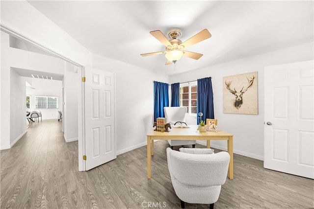 office space with baseboards, ceiling fan, visible vents, and wood finished floors