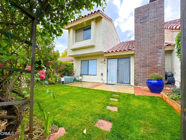rear view of property with a patio, a lawn, stucco siding, and a tiled roof