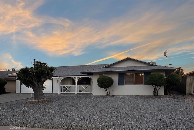 view of front of property featuring concrete driveway, a garage, stucco siding, and fence