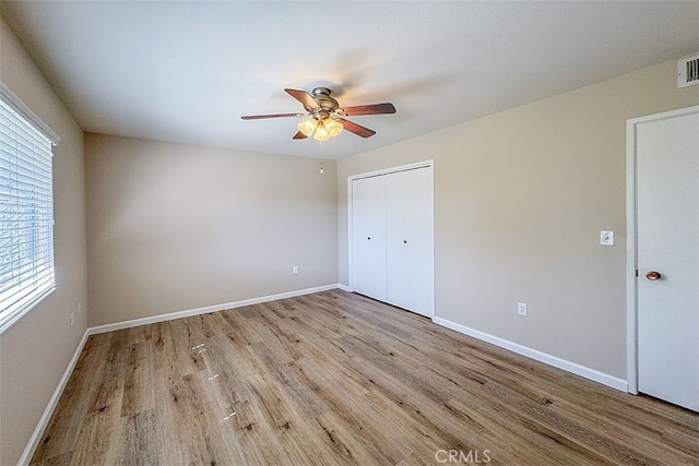 unfurnished bedroom with light wood finished floors, a closet, ceiling fan, visible vents, and baseboards