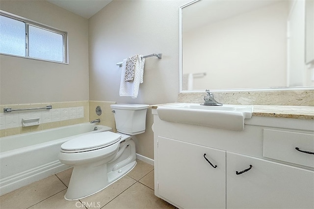 bathroom featuring tile patterned floors, a tub to relax in, toilet, vanity, and baseboards