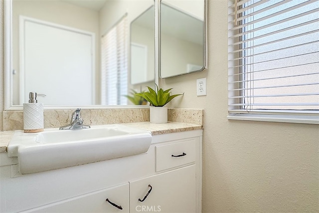 bathroom featuring a wealth of natural light, a textured wall, and vanity