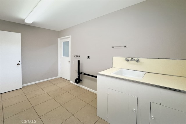 laundry area featuring light tile patterned floors, baseboards, laundry area, and a sink