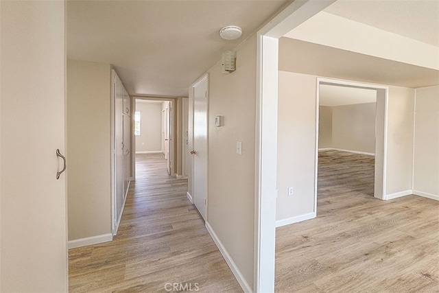 corridor with light wood-style flooring and baseboards