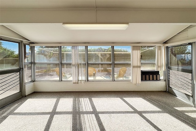 unfurnished sunroom with carpet flooring, lofted ceiling, and plenty of natural light