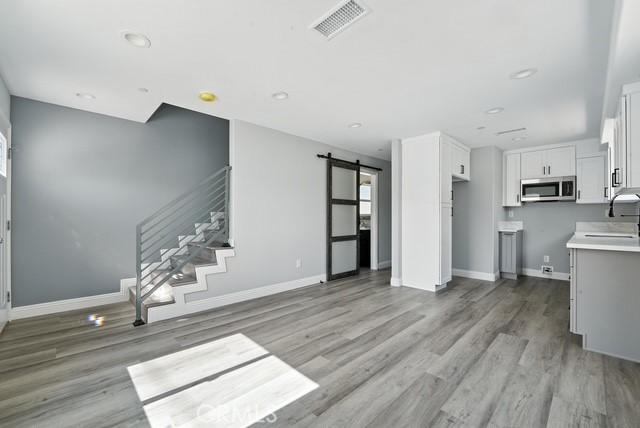 22020 Pioneer Blvd Unit A & B, Hawaiian Gardens, CA 90716 - unfurnished living room with a barn door, light wood-type flooring, stairs, and recessed lighting