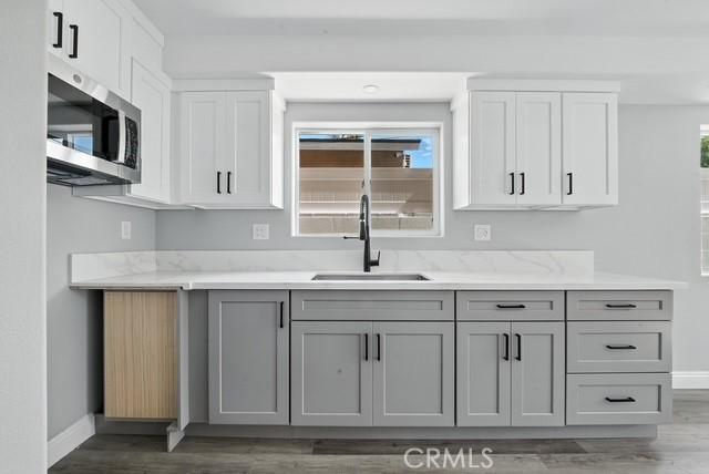 22020 Pioneer Blvd Unit A & B, Hawaiian Gardens, CA 90716 - kitchen featuring stainless steel microwave, light wood-style floors, gray cabinetry, and white cabinetry