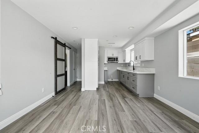 22020 Pioneer Blvd Unit A & B, Hawaiian Gardens, CA 90716 - kitchen featuring stainless steel microwave, a barn door, light wood finished floors, white cabinets, and gray cabinetry