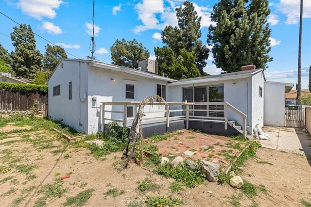 rear view of property featuring fence, a chimney, and stucco siding
