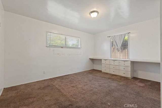 unfurnished bedroom with carpet floors and built in study area