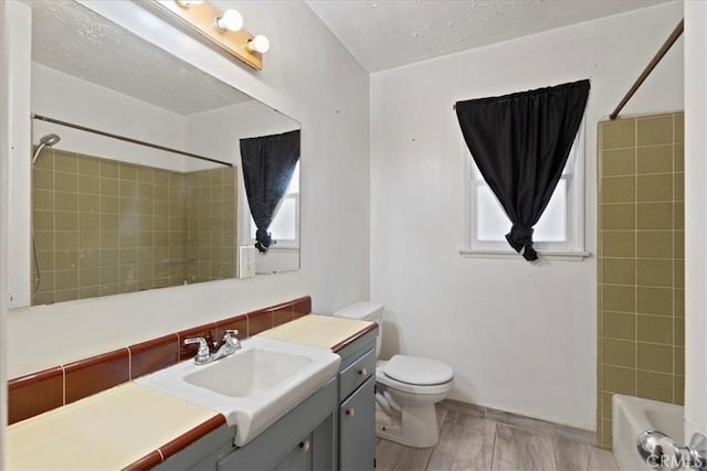 bathroom featuring toilet, baseboards, washtub / shower combination, and vanity