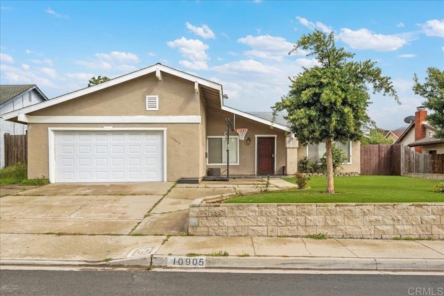 view of front of house with driveway, fence, a front lawn, and stucco siding