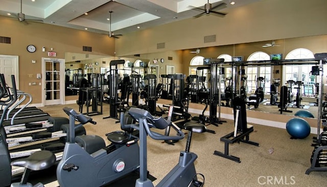gym featuring visible vents, a towering ceiling, and ceiling fan