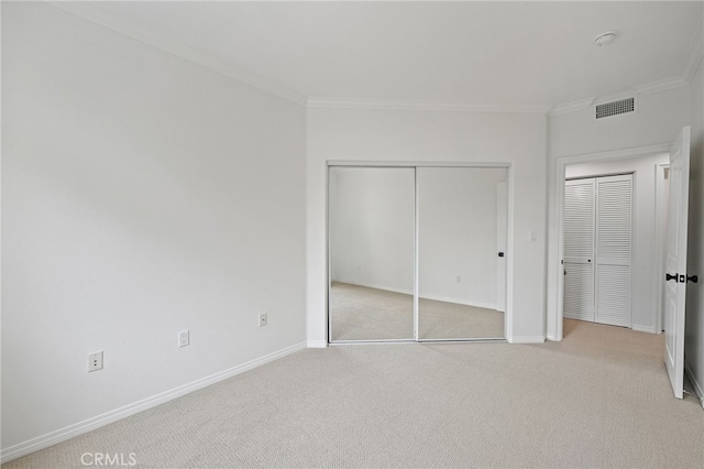 unfurnished bedroom with visible vents, baseboards, crown molding, and light colored carpet