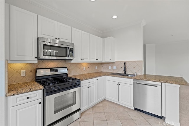 kitchen featuring appliances with stainless steel finishes, light stone counters, a sink, white cabinetry, and ornamental molding