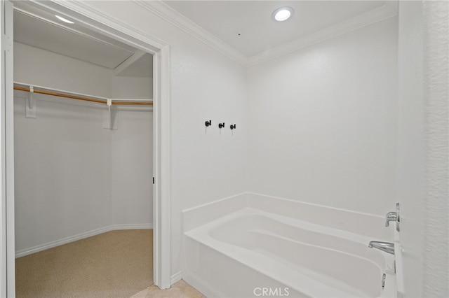 bathroom featuring a garden tub, crown molding, baseboards, a spacious closet, and recessed lighting