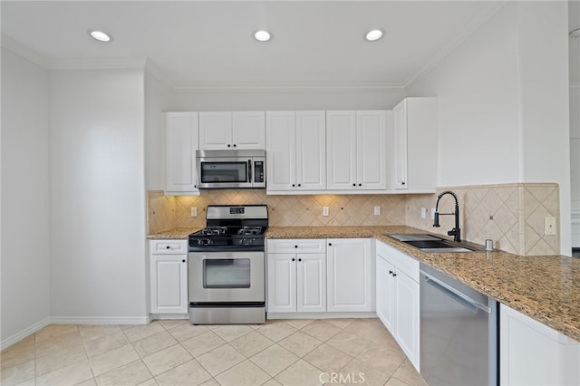 kitchen with backsplash, appliances with stainless steel finishes, a sink, light stone counters, and white cabinetry