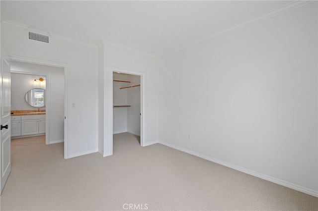 unfurnished bedroom featuring light colored carpet, a walk in closet, baseboards, visible vents, and ornamental molding