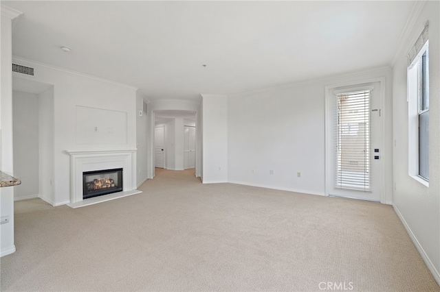 unfurnished living room featuring crown molding, light carpet, a glass covered fireplace, baseboards, and visible vents
