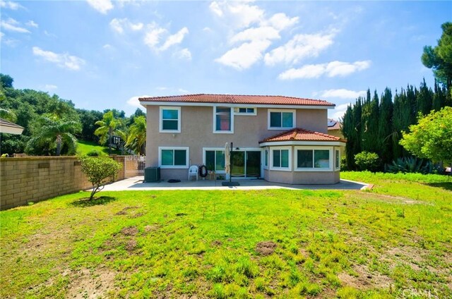 rear view of property featuring fence, a patio, stucco siding, a yard, and a tile roof
