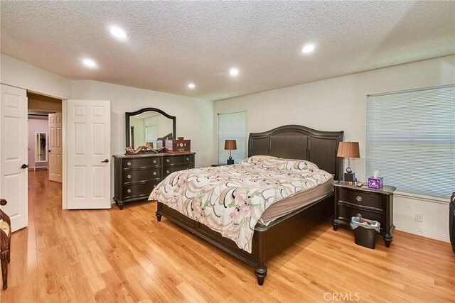 bedroom with light wood-type flooring, recessed lighting, a textured ceiling, and baseboards