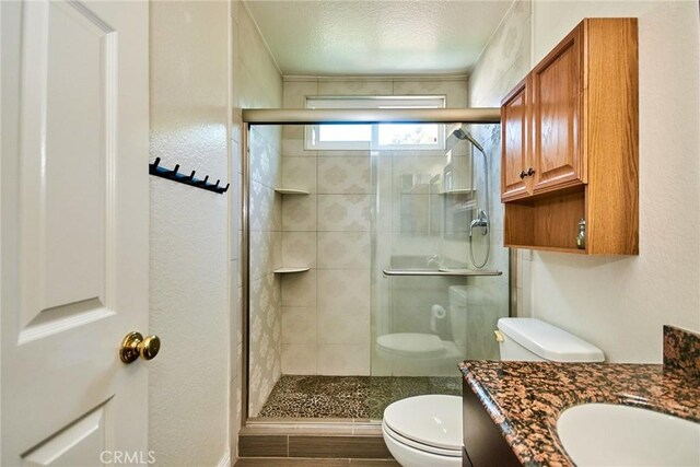 full bathroom with vanity, toilet, a textured ceiling, and a stall shower