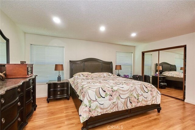 bedroom with a closet, a textured ceiling, and light wood-style flooring