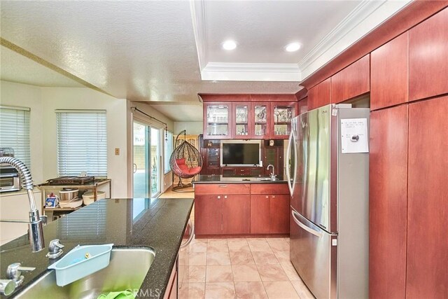 kitchen featuring crown molding, freestanding refrigerator, glass insert cabinets, a tray ceiling, and a sink