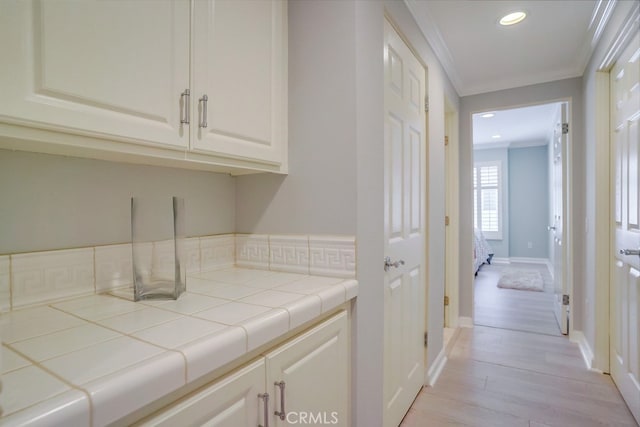 clothes washing area featuring crown molding, recessed lighting, baseboards, and light wood-style floors
