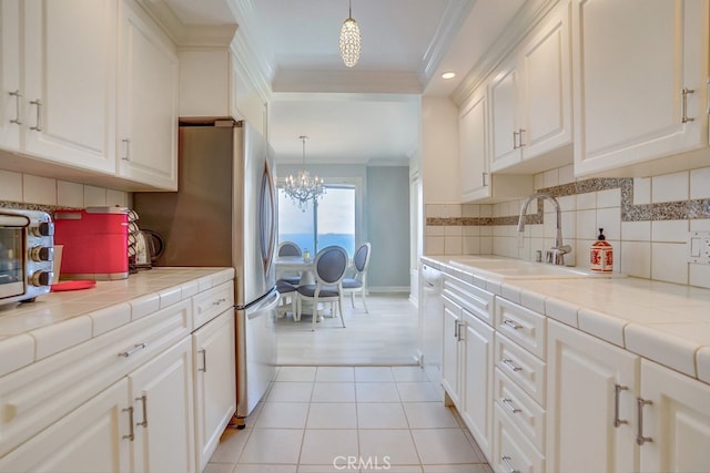 kitchen featuring crown molding, an inviting chandelier, a sink, and white cabinets